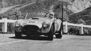 Vintage Shelby Cobra race car with number 66 on a mountain road