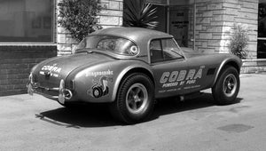 Vintage Cobra drag racing car with 'Cobra' branding with a building background